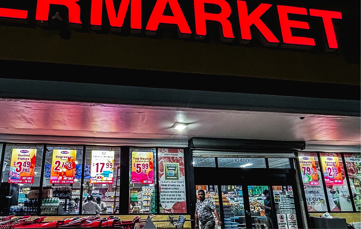 Ultra-bright LED window displays at a supermarket storefront showing digital price posters and hot sales for items like surimi flakes and top round beef.